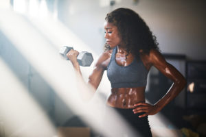 fit woman lifting iron in home gym in bonus room