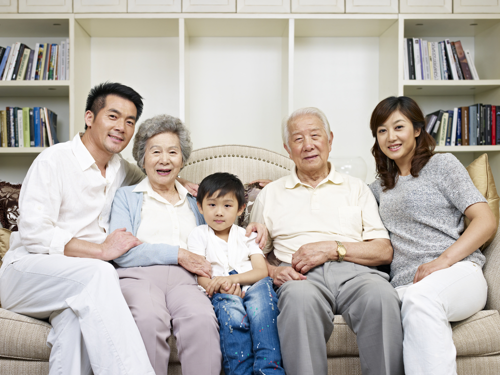 family of five spanning three generations sitting on the couch in their home